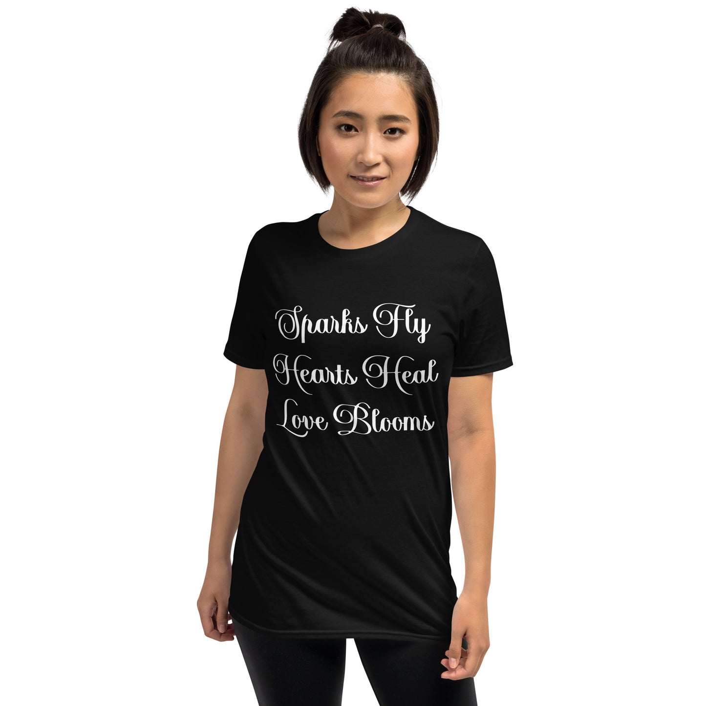 Woman wearing black Love's Journey Words t-shirt. Has the words Sparks Fly, Hearts Heal, Love Blooms.