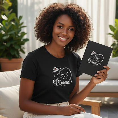 Woman wearing a black t-shirt with 'Love Blooms' design, holding a matching notebook.