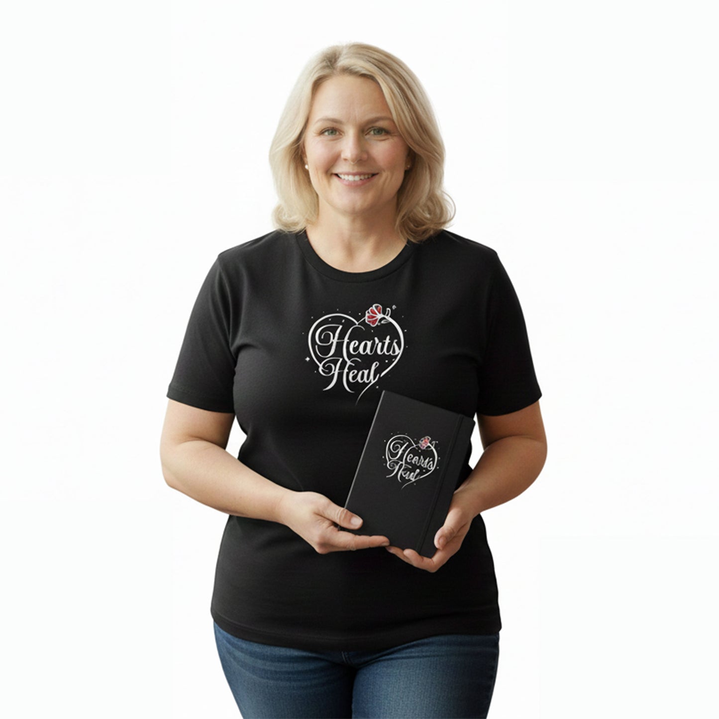 Woman wearing a black t-shirt with 'Hearts Heal' design, holding a matching notebook.