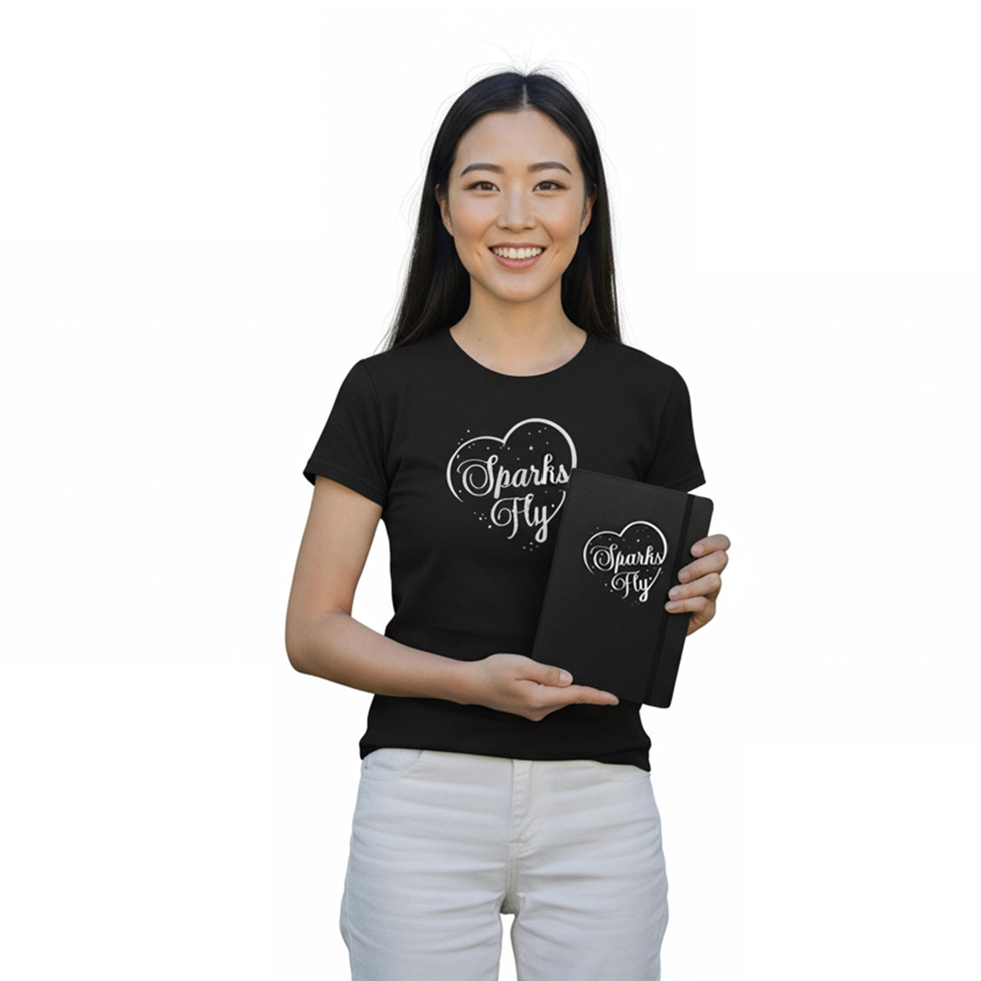 Woman wearing a black t-shirt with 'Sparks Fly' design, holding a matching notebook.