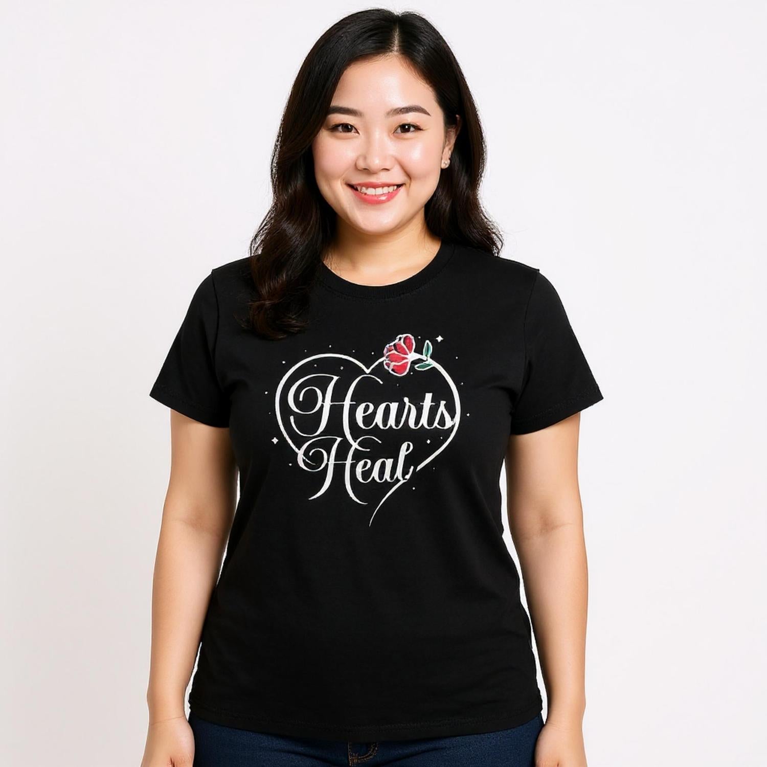 Woman wearing black short sleeved t-shirt with Hearts Heal heart design.