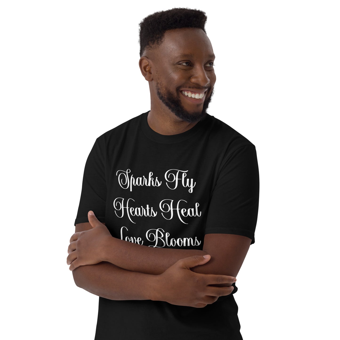 Smiling man wearing black Love's Journey Words t-shirt. Has the words Sparks Fly, Hearts Heal, Love Blooms.