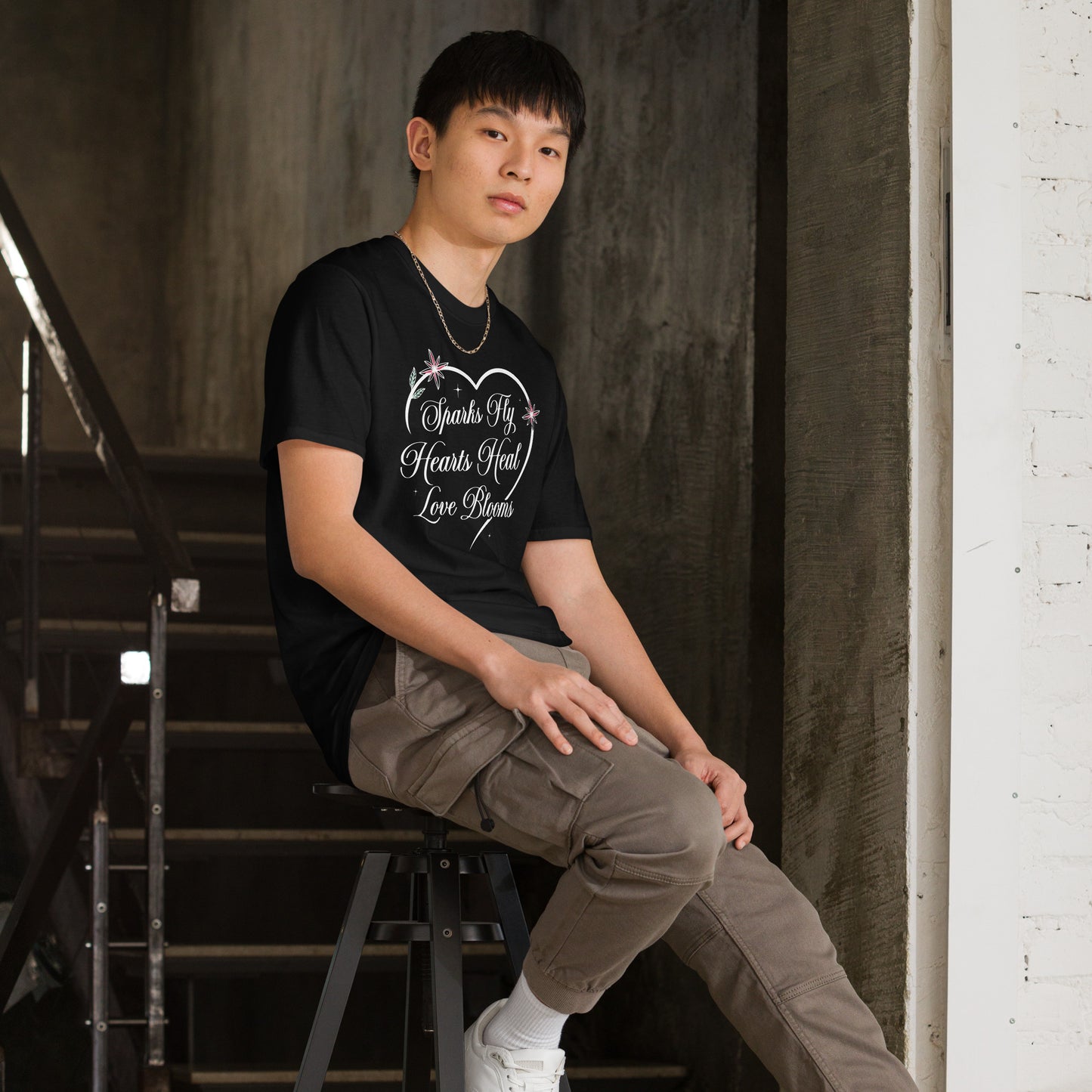 Man wearing black Love's Journey Heart t-shirt. Heart with the words Sparks Fly, Hearts Heal, Love Blooms.